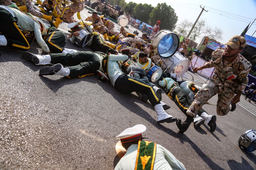 A soldier running past injured comrades lying on the ground at the scene of an attack on a military parade that was marking the anniversary of the outbreak of its devastating 1980-1988 war with Saddam Hussein's Iraq.