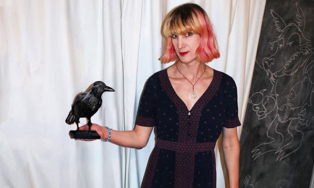 A photo of Charlie Jane Anders holding a fake bird.