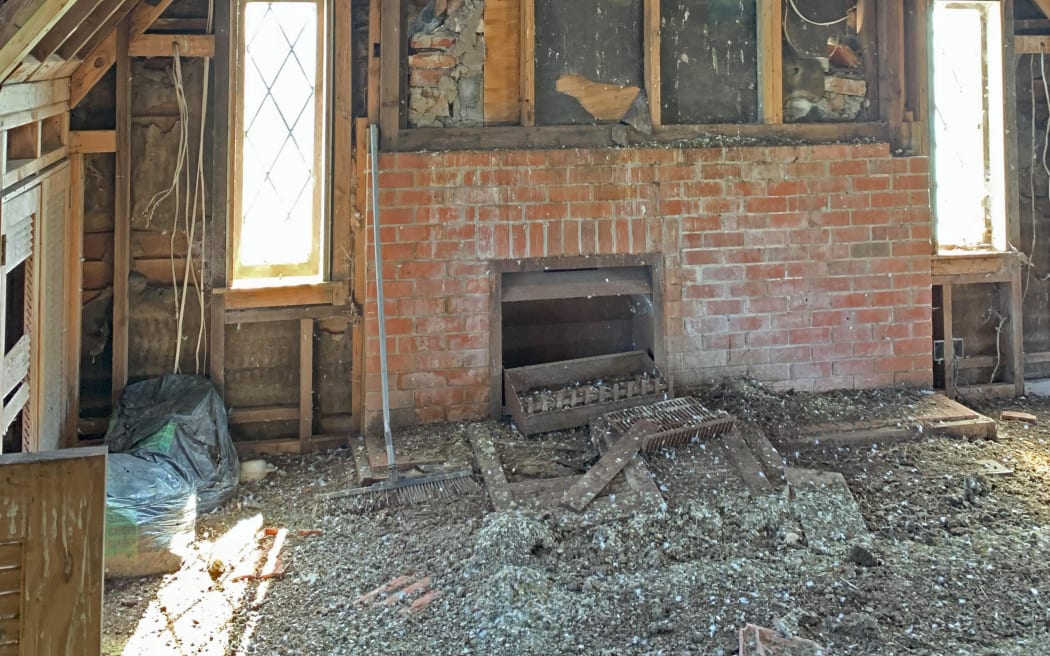 The inside of a dilapidated house, the floor is covered in a thick layer of pigeon poo.