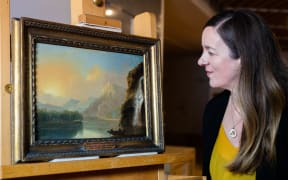 Curator of historical New Zealand art Rebecca Rice views Waterfall in Dusky Bay with Māori canoe.