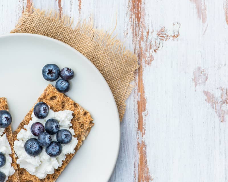 Healthy Snack from Wholegrain Rye Crispbread Crackers with  Ricotta Cheese and Fresh Blueberries on the Light Background