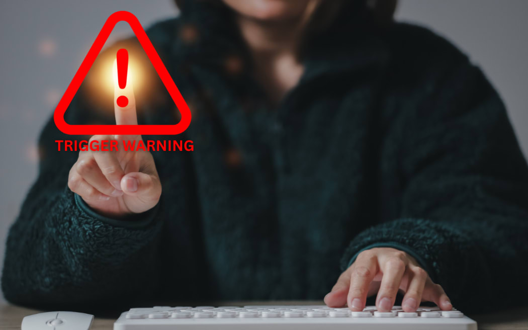 Picture of a woman clicking on a 'trigger warning' icon.