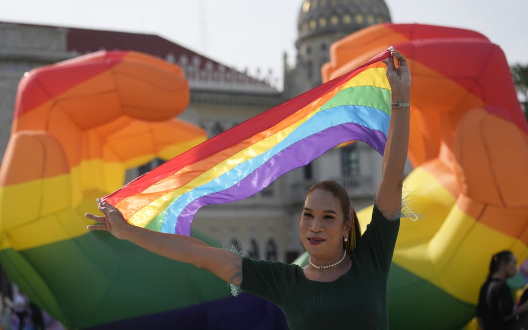 A participant holds a rainbow flag at government house in Bangkok, Thailand, Tuesday, June 18, 2024. Thailand’s Senate voted overwhelmingly on Tuesday to approve a marriage equality bill, clearing the last legislative hurdle for the country to become the first in Southeast Asia to enact such a law. (AP Photo/Sakchai Lalit)