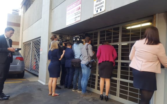 Political reporters peeking for clues through a garage door in the Beehive.