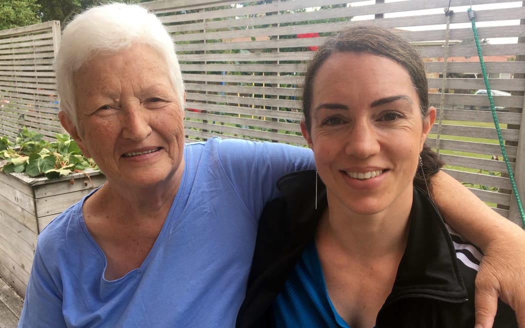 A grandmother with sort while hair sits outside with her granddaughter in her 30s
