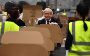 Britain's Prime Minister and Conservative party leader Boris Johnson helps out on the packing production line in a fulfilment centre for The Hut Group (THG) in Warrington, in north-west England on December 10, 2019,
