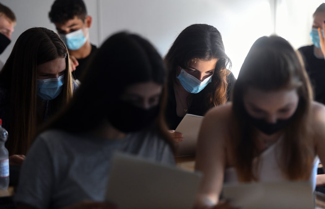 Students of the eleventh grade sit with face masks in a classroom of the Phoenix high school in Dortmund, western Germany, on 12 August 2020, amid the novel coronavirus COVID-19 pandemic.