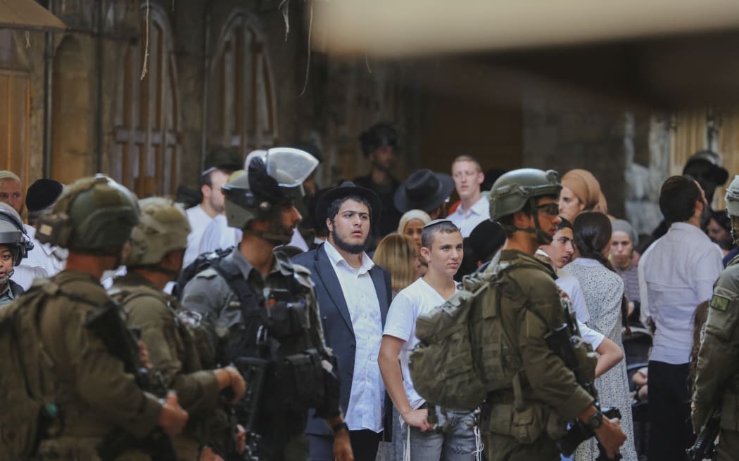 A group of Israeli settlers gather in Hebron’s old city, West Bank on August 16, 2025. Their entry into Palestinian neighborhoods was carried out under army protection. (Photo by Mosab Shawer / Middle East Images via AFP)