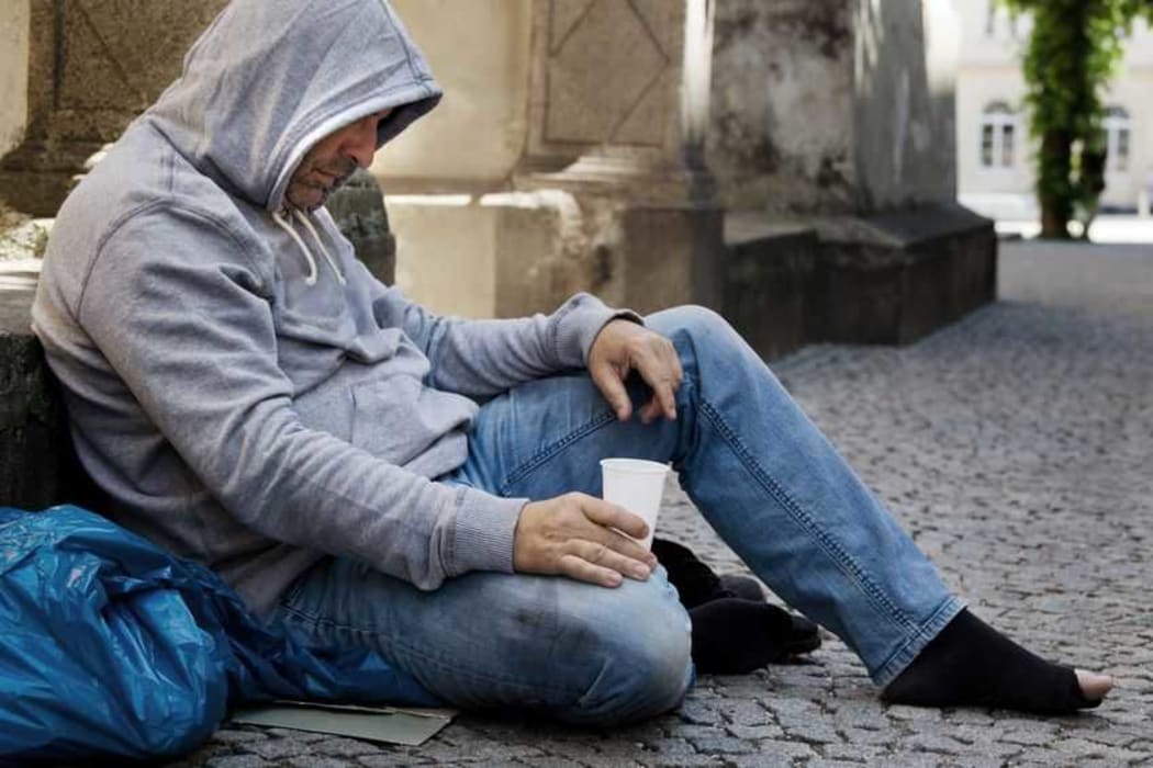 A homeless man begging on the street.