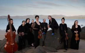 Australian early instrument ensemble Van Diemen's Band pose with instruments on a beach.