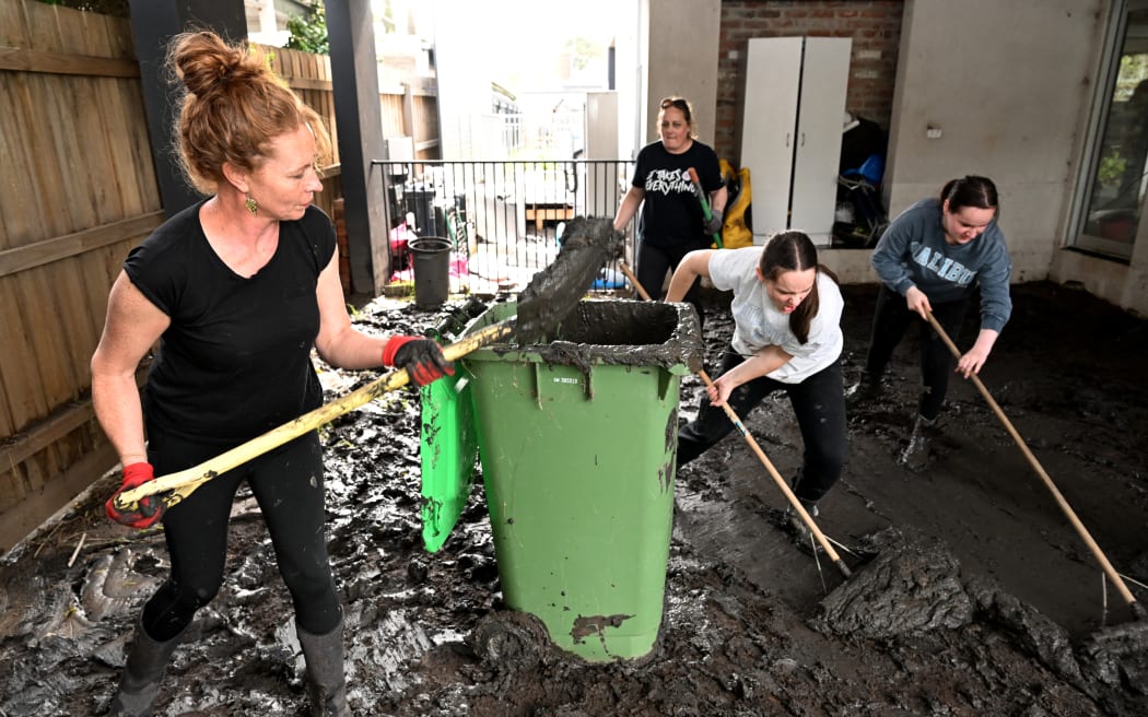 People clear mud from a property damaged by floods in the Melbourne suburb of Maribyrnong on October 15, 2022. - Australia reported the first fatality from days of widespread flash flooding on October 15, 2022 despite heavy rains easing and flood levels topping out across much of the southeast. Hundreds of homeowners began a long clean-up after storm waters engulfed streets, houses and cars across three states, with Melbourne suburbs among the worst hit. (Photo by William WEST / AFP)