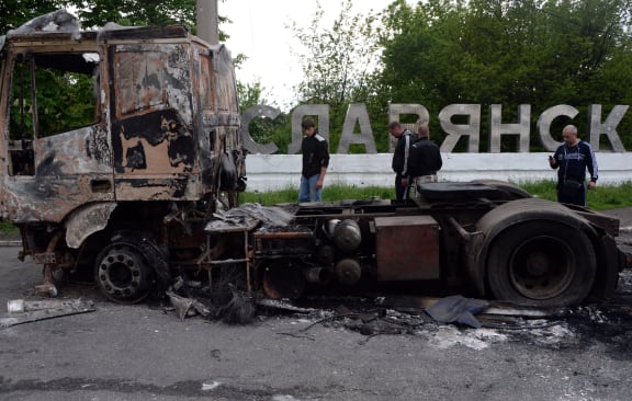 People walk past a burned truck near the eastern Ukranian city of Sloviansk.