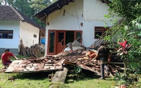 Villagers beside a collapsed house at Tegalrejo village, in Blitar, East Java, after a 6.0 magnitude earthquake struck off the coast of Indonesia's Java island.