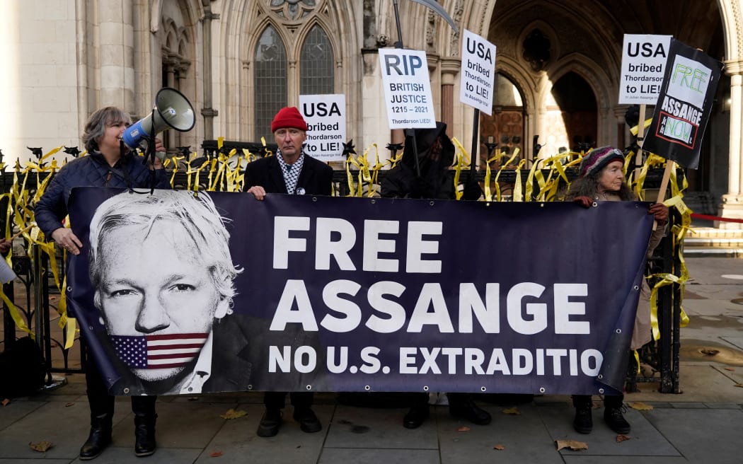 Supporters of WikiLeaks founder Julian Assange, hold placards outside the Royal Courts of Justice in London on December 10, 2021. Two judges in London will on Friday rule on a US government appeal against a decision not to extradite WikiLeaks founder Julian Assange from Britain. (Photo by Niklas HALLE'N / AFP)