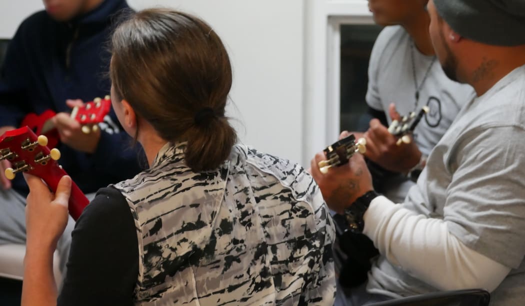 Christchurch Men's prisoners play the ukelele with a member of the CSO