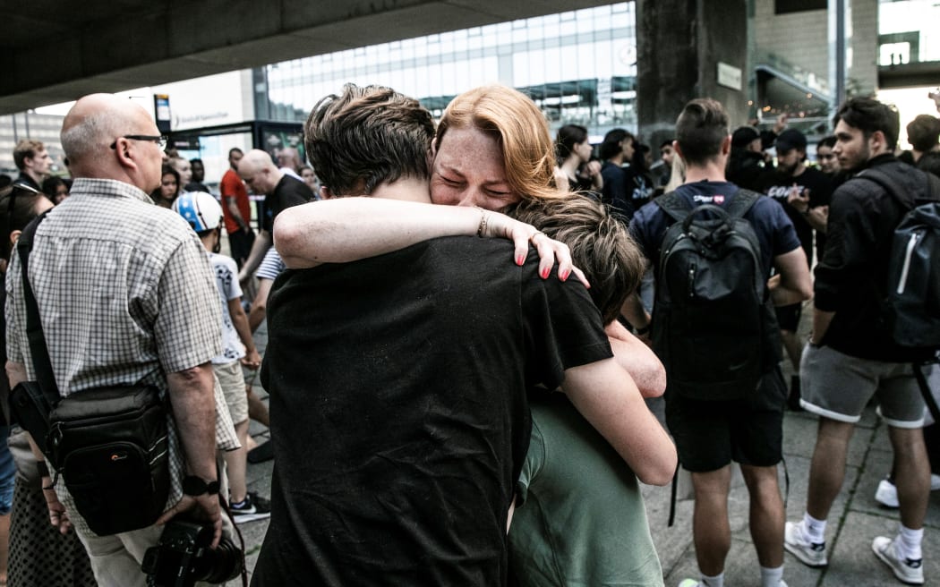 People hug each other outside Fields shopping mall, where a gunman killed three people and wounded several others in Copenhagen on July 3, 2022. - A 22-year-old Danish man was arrested after the shooting but his motives were unclear, police said. (Photo by Olafur STEINAR GESTSSON / Ritzau Scanpix / AFP) / Denmark OUT