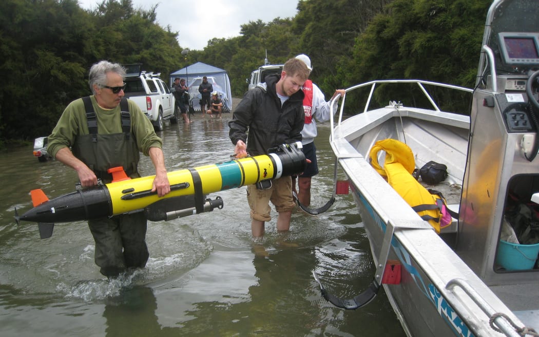 Scientists load an autonomous underwater vehicle onto the side of a support boat during a comprehensive survey of the 800-hectare Lake Rotomahana