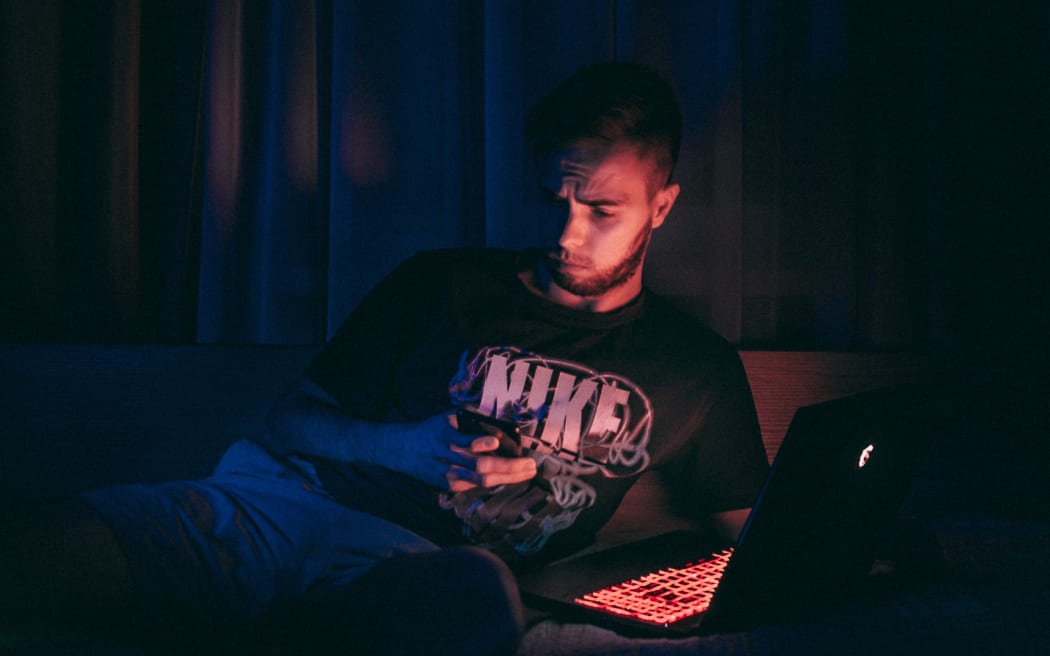 young man on laptop in the dark