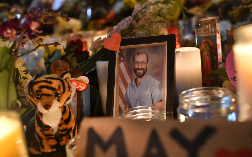 A photo of Alex Pretti is displayed at a makeshift memorial in his honor in the area where he was shot dead by federal immigration agents in Minneapolis, Minnesota, on January 26, 2026. On January 24, federal agents shot and killed Alex Pretti, a 37-year-old ICU nurse, while scuffling with him on an icy roadway in Minneapolis, less than three weeks after an immigration officer fired on Renee Good, also 37, killing her in her car. The fatal shootings has reignited accusations that federal agents enforcing US President Donald Trump's militarized immigration crackdown are inexperienced, under-trained and operating outside law enforcement norms. (Photo by Octavio JONES / AFP)