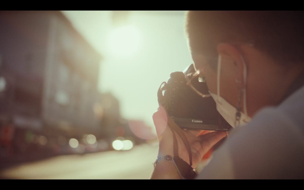 Becki Moss taking photos on Karangahape Road bathed in the afternoon light