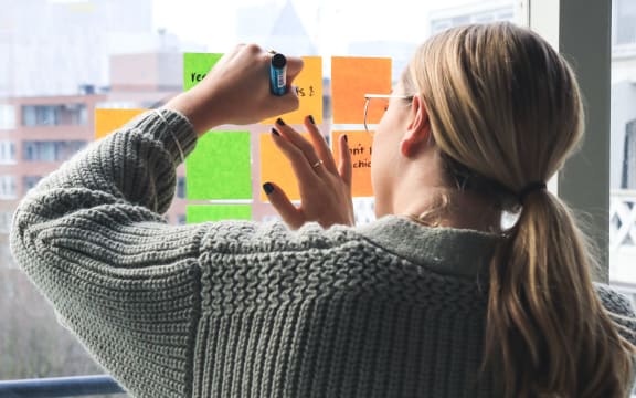 woman writing on post-it notes taped to a window