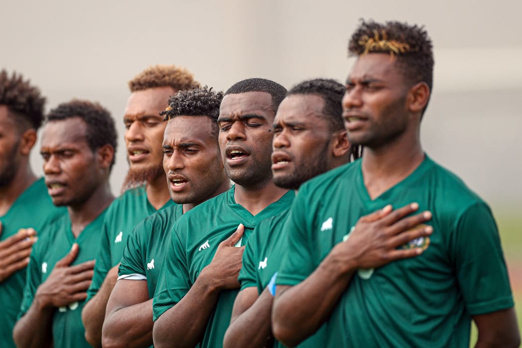 Ronaldo Wilkins (centre) sings anthem with his team