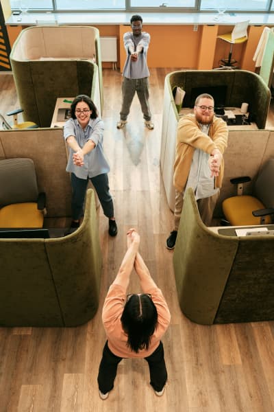 A group of office workers stretch their shoulders in a diamond formation.