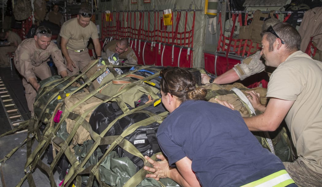 Air Commodore Darryn Webb (top left) helps secure a load on the Air Force C-130 Hercules aircraft.