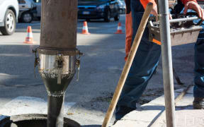 A Man Is Commanding A Machine For Cleaning The Manholes In The Street