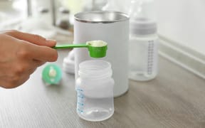 Preparing baby milk formula on wooden table closeup