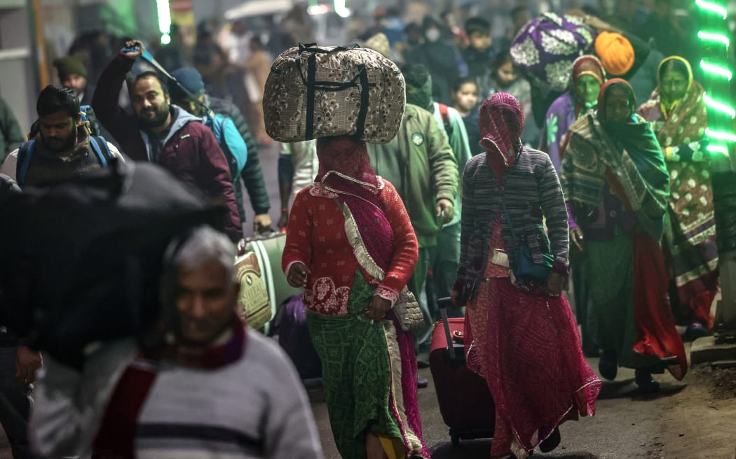 Hindu pilgrims with their belongings leave a railway station as they move towards Sangam, the confluence of Ganges, Yamuna and mythical Saraswati rivers, to take part in the Maha Kumbh Mela festival in Prayagraj on January 12, 2025. The millennia-old Kumbh Mela, a sacred show of religious piety and ritual bathing that opens January 13, is held at the site where the holy Ganges, Yamuna and the mythical Saraswati rivers meet. (Photo by Niharika KULKARNI / AFP)