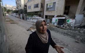 A Palestinian woman reacts as she walks along a street damaged during an Israeli army raid in the Nur Shams camp near the city of Tulkarem in the Israeli-occupied West Bank, on August 28, 2024. At least 10 Palestinians were killed in Israeli raids and strikes in several towns in the north of the occupied West Bank, a spokesman for the Red Crescent said on August 28.