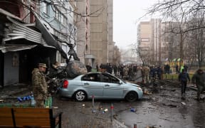 Military and onlookers stand at the site where a helicopter crashed near a kindergarten outside the capital Kyiv, killing Sixteen people, including two children and Ukrainian interior minister, on January 18, 2023, amid the Russian invasion of Ukraine. (Photo by Sergei Supinsky / AFP)