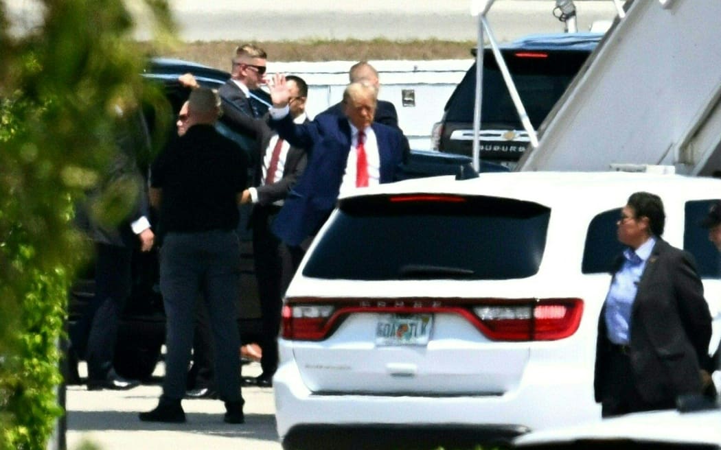 Former US President Donald Trump waves as he boards his plane at Palm Beach International Airport in West Palm Beach, Florida, on 3 April 2023. - Former US President Donald Trump is to be booked, fingerprinted, and will have a mugshot taken at a Manhattan courthouse on the afternoon of April 4, 2023, before appearing before a judge as the first ever American president to face criminal charges. Trump left his Mar-a-Lago residence in a dozen-vehicle motorcade as a dozen supporters shouted as the former president passed by to show their support for him. (Photo by CHANDAN KHANNA / AFP)