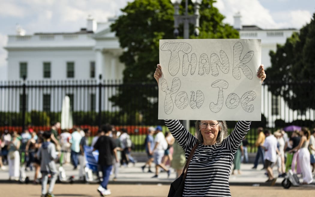 A woman holds a sign reading 