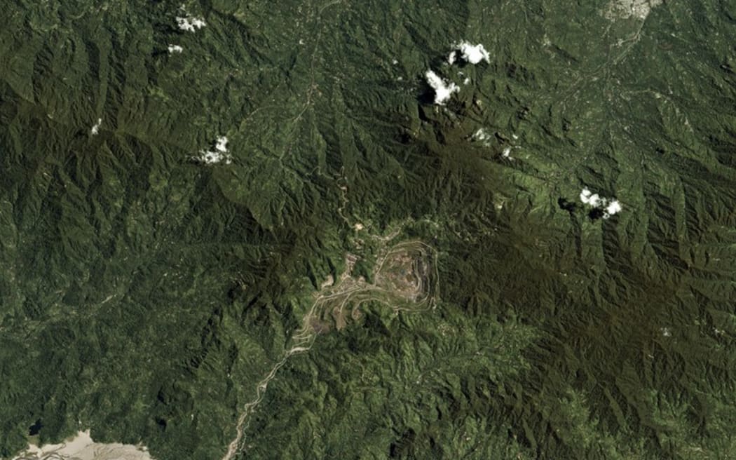 Satellite photo of the abandoned former Rio Tinto Panguna mine (center) in Bougainville, with the regional capital Arawa (top left) and tailings waste spilling downstream (bottom right), pictured Sept. 26, 2017. [Trevor Hammond/Planet Labs via Reuters]