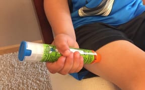 A young boy demonstrates how to use an EpiPen to treat anaphylaxis.