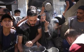Palestinians line up to receive a hot meal at a food distribution point in Gaza City on 27 June 2025. After more than 20 months of devastating conflict, rights groups say Gaza's population of more than two million face famine-like conditions.