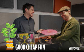 An image of two young men laughing together as they select records to play on a turntable.