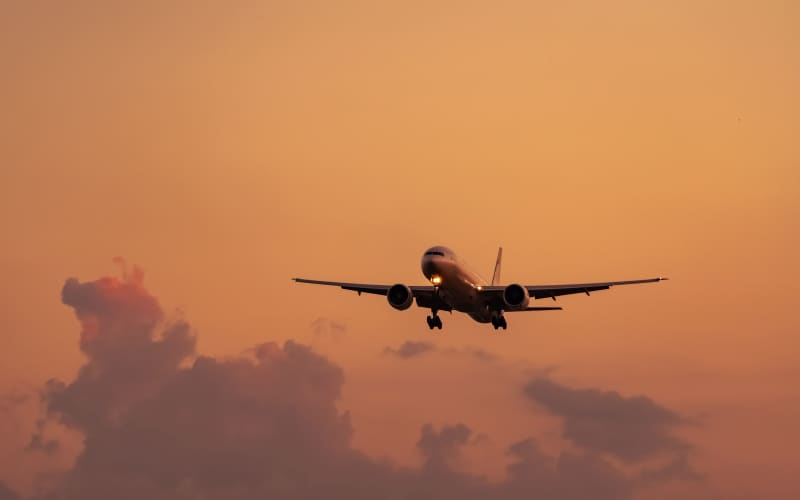Commercial airline. Passenger plane landing at airport with beautiful sunset sky and clouds. Arrival flight. Airplane flying in a line for landing. Aircraft open light in the evening flight.