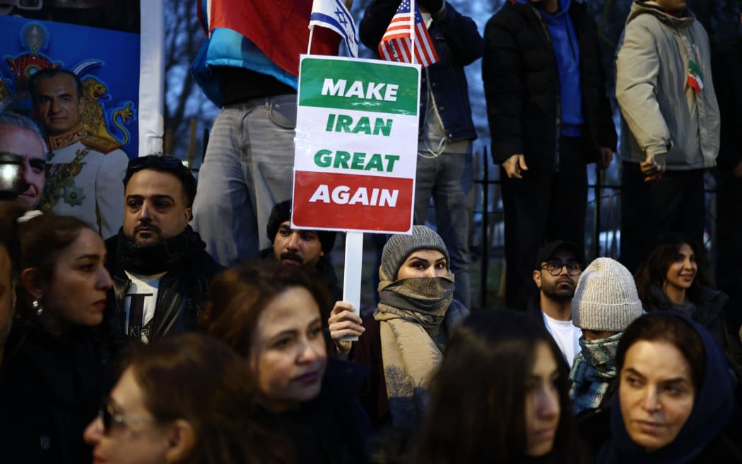Anti-Iranian regime protesters wave Iranian flags during a gathering outside the Iranian Embassy, central London, on January 12, 2026. (Photo by Henry NICHOLLS / AFP)