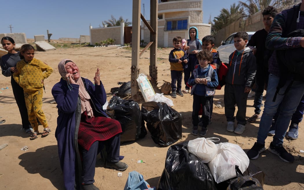 A woman who fled with others the Al-Shifa hospital and its vicinity in Gaza City reacts as she sits amid some of her belongings in central Gaza, on March 21, 2024. Israel's army was on March 21 four days into a raid at Al-Shifa, Gaza's largest hospital, where the military says Hamas was operating from among patients and displaced civilians. (Photo by AFP)