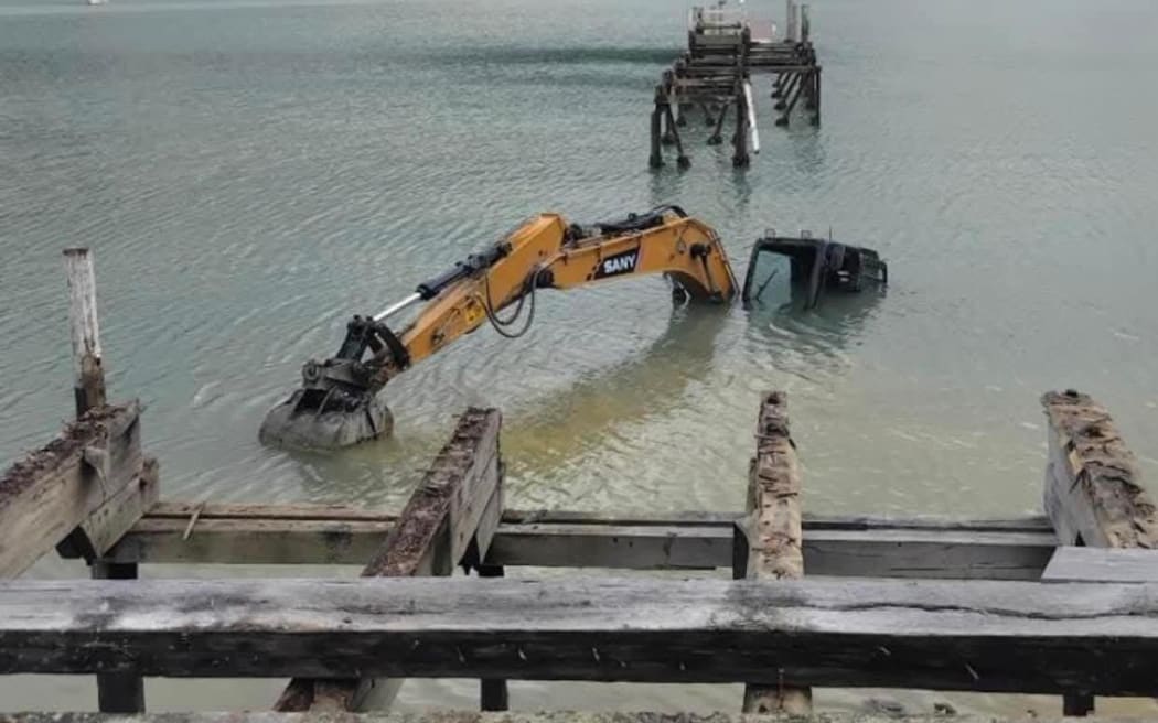 A digger working on the replacement of Waitara Bay’s new jetty has become stuck in the sand and submerged.