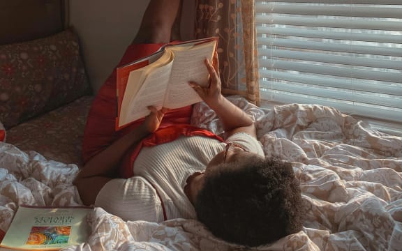 Teenager reading a book in bed.