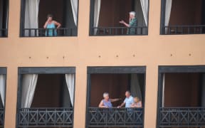 Tourists stand on the balconies of their rooms at a hotel in Tenerife, in Spain's Canary Islands. Hundreds of people were confined to their rooms after an Italian tourist was hospitalised with a suspected case of coronavirus.