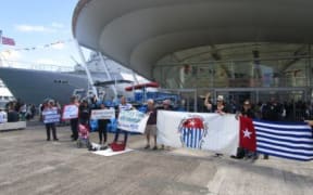 Demonstrators in Auckland hold up Morning Star flag to Indonesian sailors