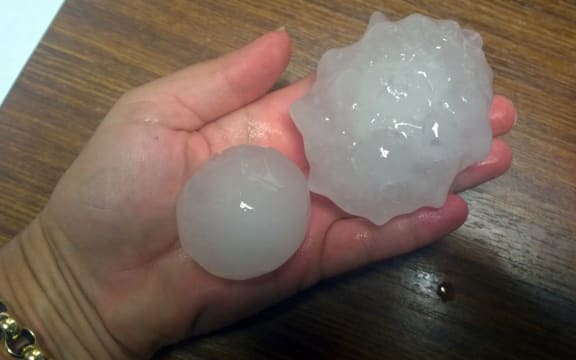 A supplied image obtained Wednesday, Dec. 16, 2015 of Cronulla local Beth, holds golf-ball sized hail stones in Cronulla, Sydney.