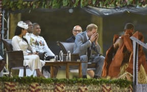 Prince Harry drinks kava as his wife Meghan, the Duchess of Sussex, looks on at a traditional welcome ceremony after they arrived in Suva, Fiji.