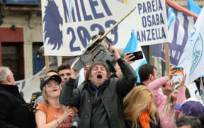 Picture released by AG La Plata showing the presidential candidate for La Libertad Avanza party, Javier Milei (C), waving a chainsaw between his sister Karina Milei (R) and Buenos Aires Province governor candidate Carolina Piparo, during a political rally in La Plata, Buenos Aires Province, Argentina, on September 12, 2023. Argentina holds presidential elections on October 22, 2023. With a month to go, the election remains eminently open and the economy at the heart of the debates, with a great divide between the ultraliberal Javier Milei's promise to "slash" public spending and the government camp's showering of subsidies to "lend a hand" to Argentines bled dry by inflation. His main rivals will be former security minister Patricia Bullrich on the right, and economy minister Massa from the ruling centre-left coalition. (Photo by Marcos GOMEZ / AG La Plata / AFP) / RESTRICTED TO EDITORIAL USE - MANDATORY CREDIT "AFP PHOTO / AG LA PLATA / MARCOS GOMEZ" - NO MARKETING - NO ADVERTISING CAMPAIGNS -...
