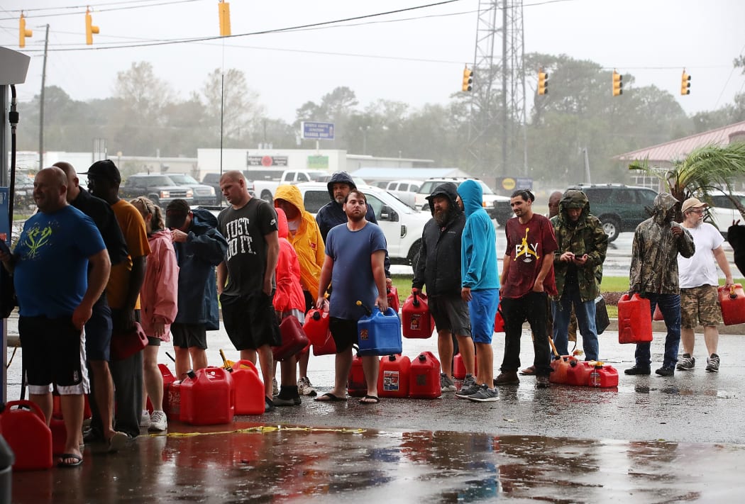 People wait in line to fill up their gas cans at a gas station that was damaged when Hurricane Florence hit Wilmington, North Carolina.